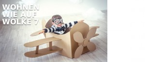 Kind sitzt in einem selbstgebastelten Flugzeug aus Karton