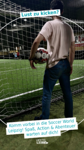 Junger Mann steht mit einem Fußball unter dem Arm an einem Fußballfeld der Soccerworld Leipzig