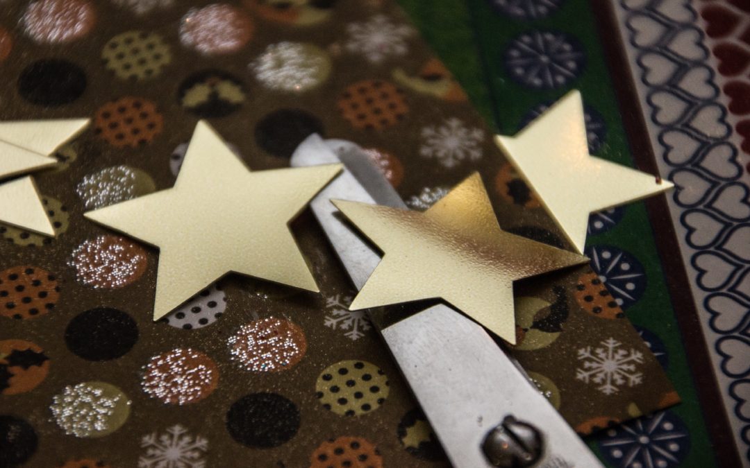 Goldene Sterne und eine Bastelschere auf buntem Papier in einer WOGETRA Wohnung.