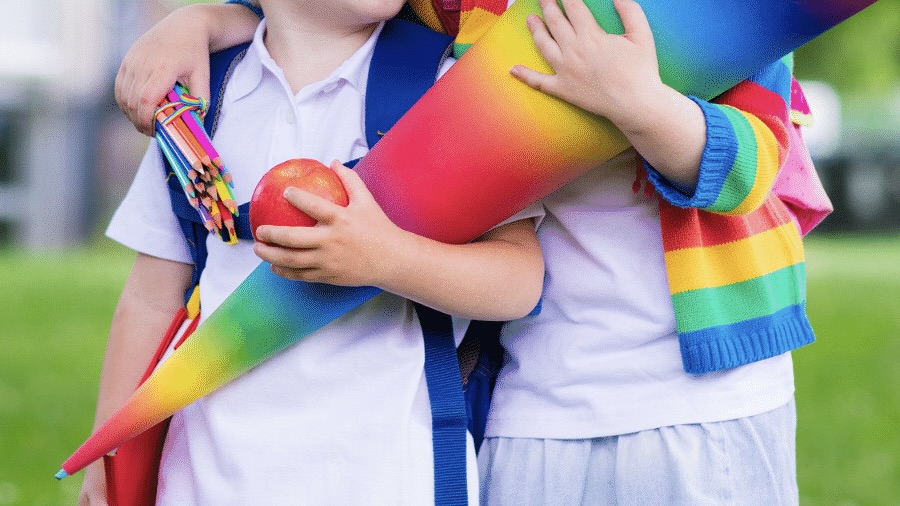Zwei Kinder mit bunten Zuckertüten und Schulranzen bei der Einschulung.