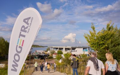 WOGETRA-Flagge weht im Wind, im Hintergrund das Sommerfest-Gelände am Schladitzer See.